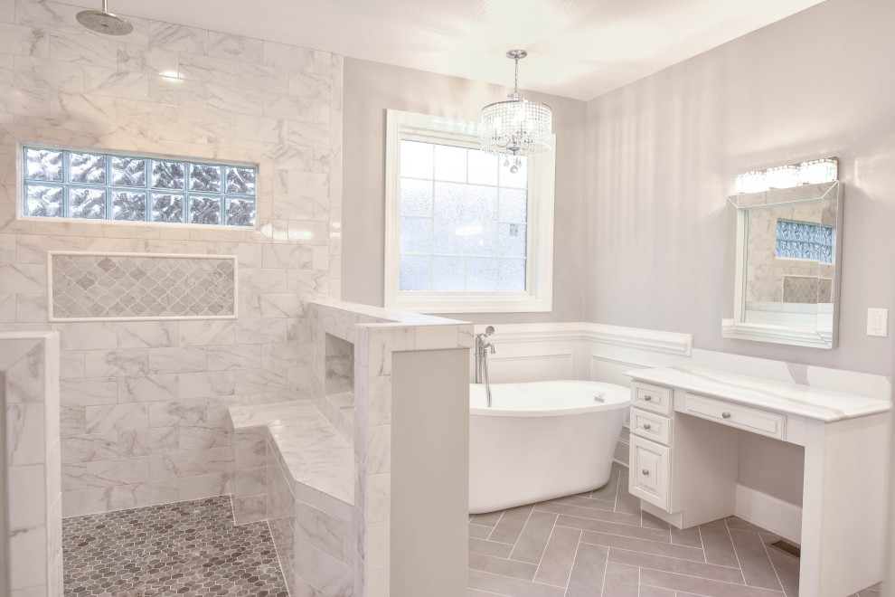 Bild på ett vintage vit vitt en-suite badrum, med luckor med upphöjd panel, vita skåp, ett fristående badkar, en hörndusch, grå kakel, marmorkakel, grå väggar, klinkergolv i porslin, bänkskiva i kvartsit, grått golv och med dusch som är öppen