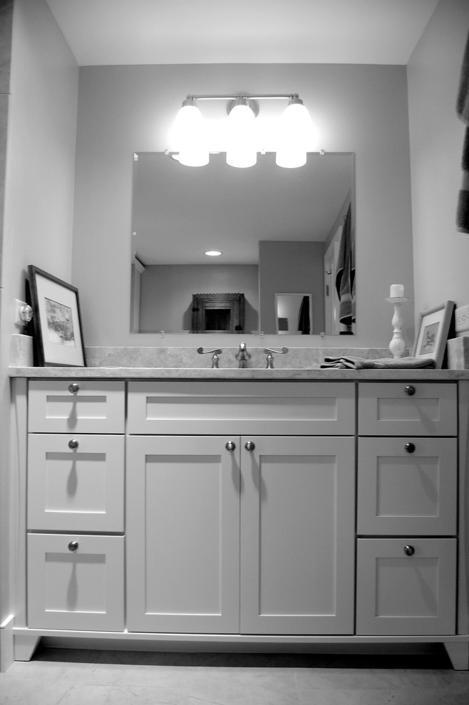 Aménagement d'une salle de bain classique avec une baignoire posée, une douche d'angle, un carrelage beige, des carreaux de porcelaine, un mur beige, un sol en carrelage de porcelaine, un lavabo encastré et un plan de toilette en marbre.