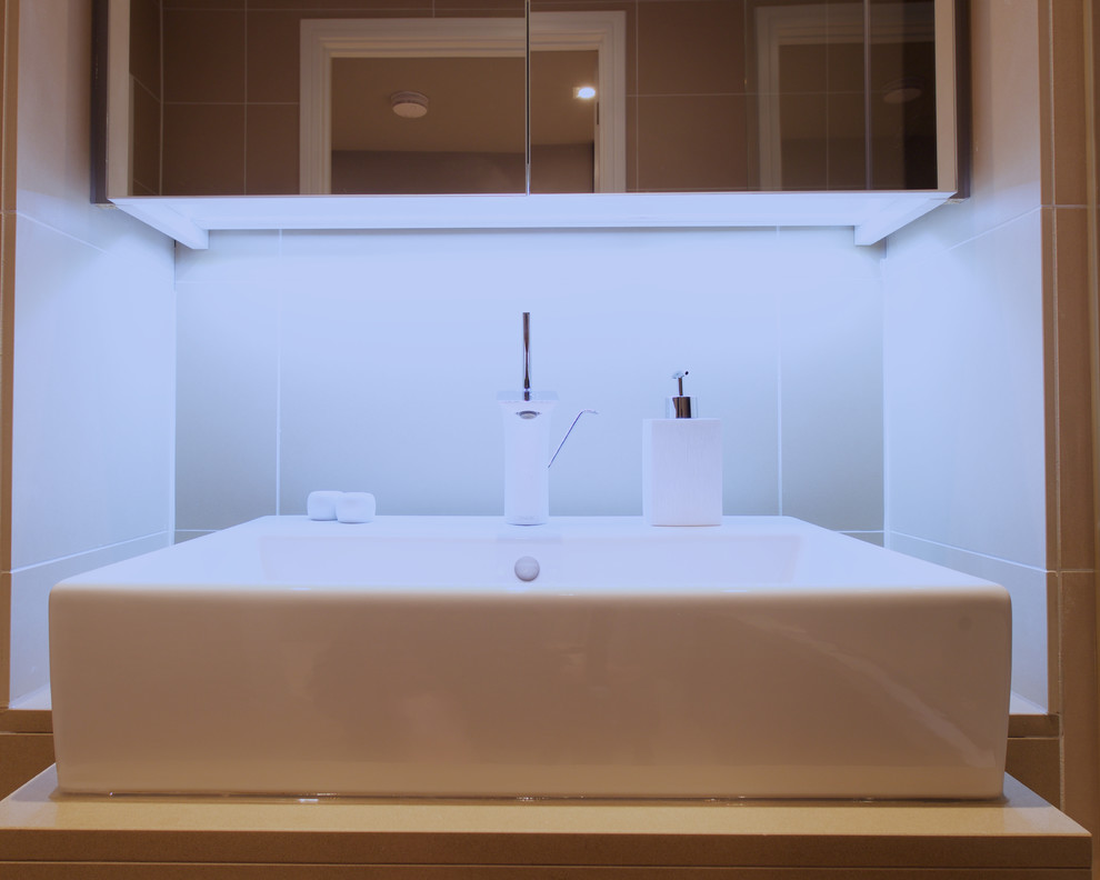 Immagine di una stanza da bagno padronale design con lavabo a consolle, ante di vetro, top in pietra calcarea, vasca ad alcova, vasca/doccia, WC sospeso e pavimento in pietra calcarea