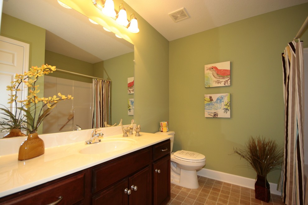 Inredning av ett amerikanskt mellanstort en-suite badrum, med luckor med infälld panel, skåp i mellenmörkt trä, ett badkar i en alkov, en dusch i en alkov, en toalettstol med separat cisternkåpa, gröna väggar, vinylgolv, ett integrerad handfat och bänkskiva i kvarts