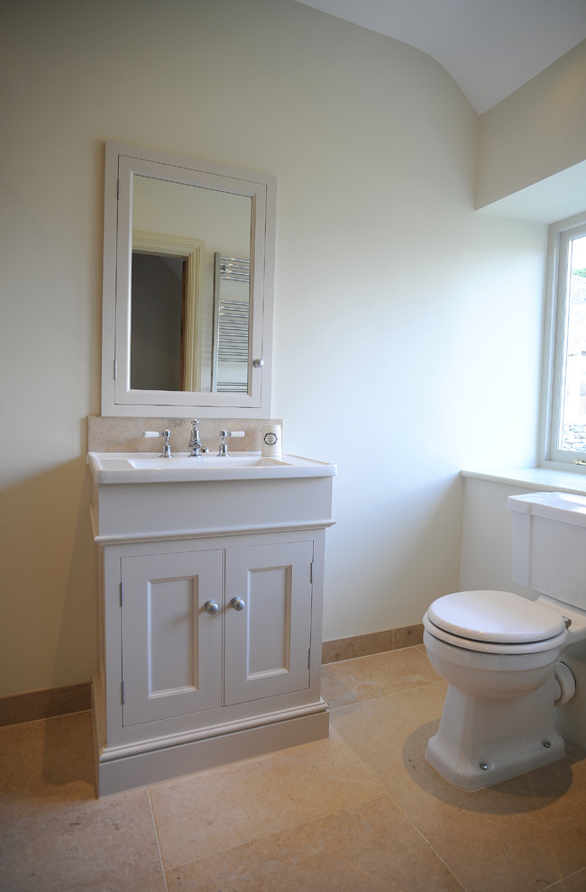 Immagine di una piccola stanza da bagno padronale classica con lavabo da incasso, ante con riquadro incassato, vasca da incasso, vasca/doccia, WC monopezzo e pavimento in pietra calcarea
