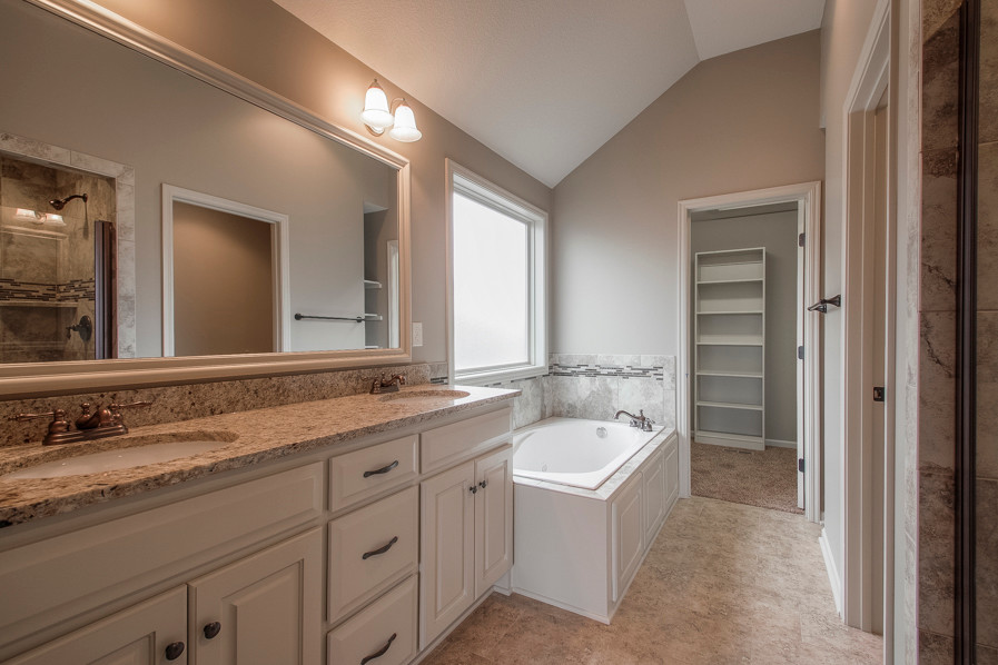 Exemple d'une salle de bain principale chic en bois brun de taille moyenne avec un placard avec porte à panneau surélevé, un plan de toilette en granite, une baignoire posée, un carrelage beige, des carreaux de céramique, un mur gris et un sol en carrelage de céramique.