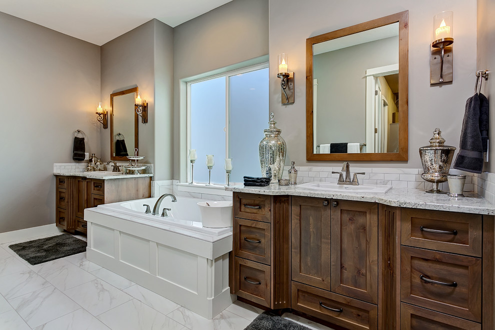 Diseño de cuarto de baño principal de estilo americano con armarios estilo shaker, puertas de armario de madera oscura, bañera encastrada y encimera de granito