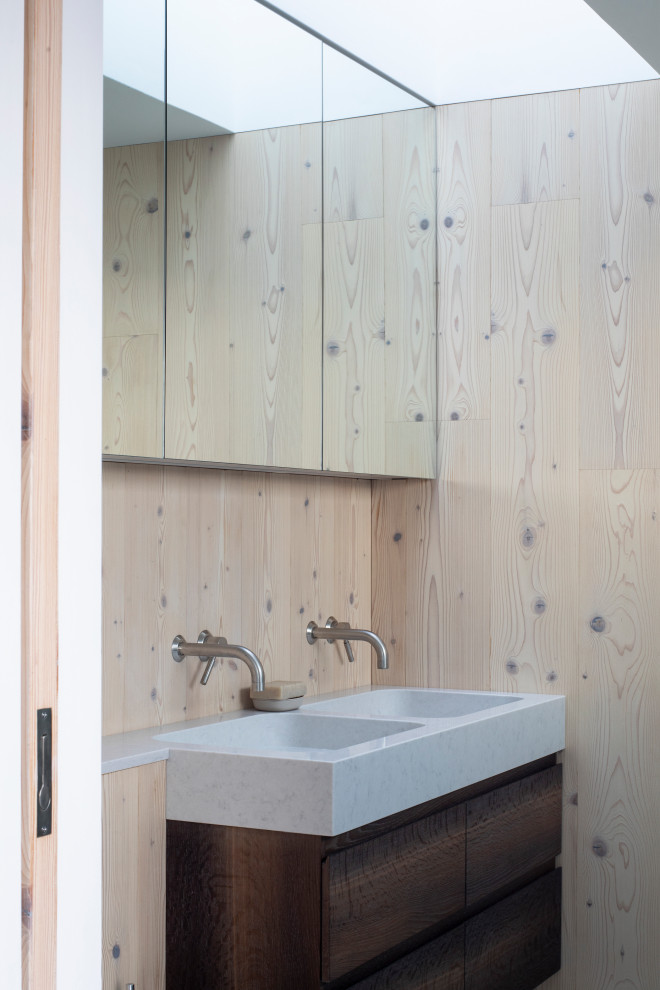 サセックスにあるモダンスタイルのおしゃれな浴室 (フラットパネル扉のキャビネット、濃色木目調キャビネット、ベージュの壁、一体型シンク、グレーの洗面カウンター、洗面台2つ、フローティング洗面台、板張り壁) の写真