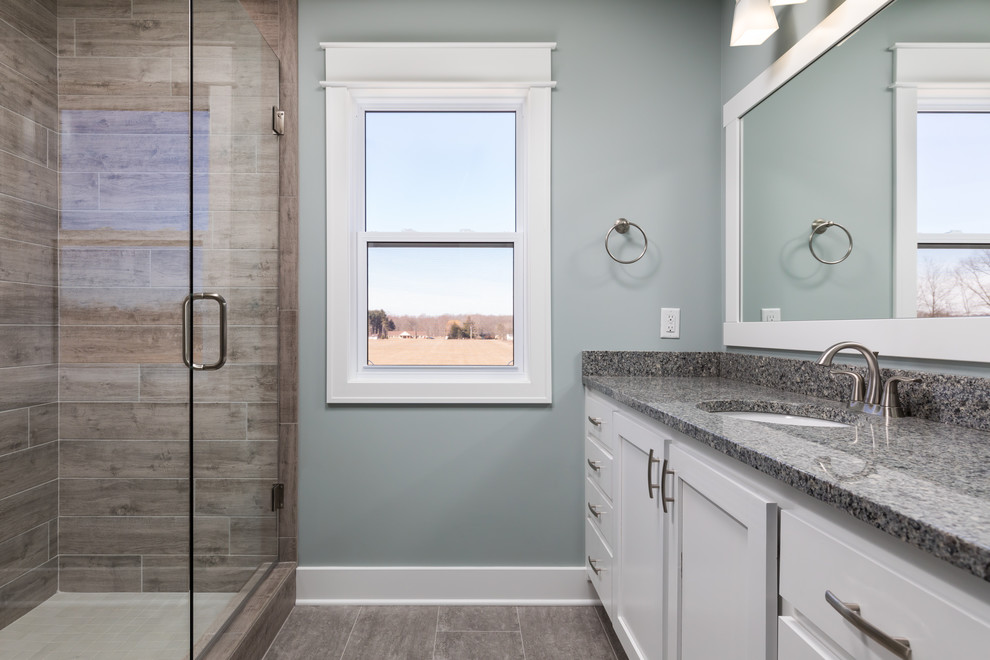 Idéer för ett stort amerikanskt grå en-suite badrum, med luckor med infälld panel, vita skåp, en dusch i en alkov, en toalettstol med separat cisternkåpa, grå kakel, porslinskakel, blå väggar, vinylgolv, ett undermonterad handfat, granitbänkskiva, grått golv och dusch med gångjärnsdörr