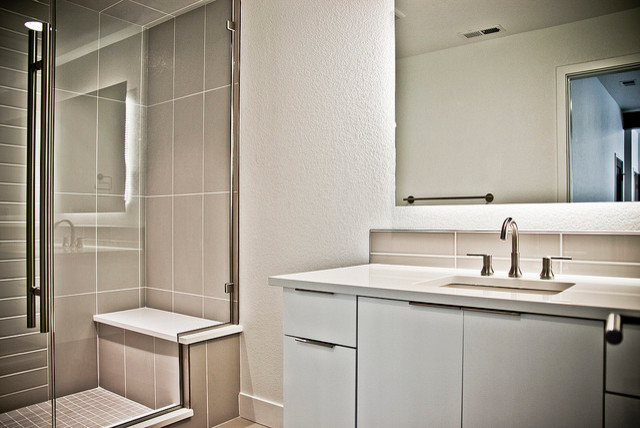 Bild på ett stort funkis badrum med dusch, med ett undermonterad handfat, släta luckor, vita skåp, bänkskiva i kvarts, en dusch i en alkov, grå kakel, keramikplattor, vita väggar och klinkergolv i porslin