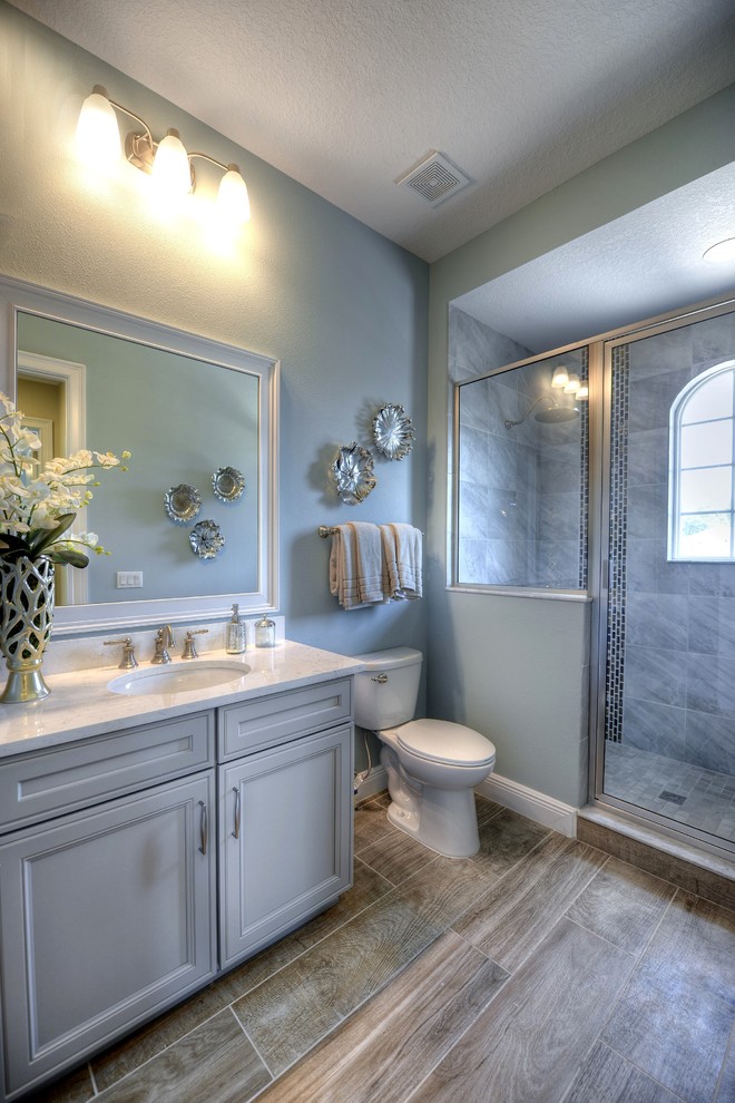 Exempel på ett mellanstort badrum med dusch, med luckor med upphöjd panel, grå skåp, en dusch i en alkov, blå väggar, klinkergolv i keramik och ett undermonterad handfat