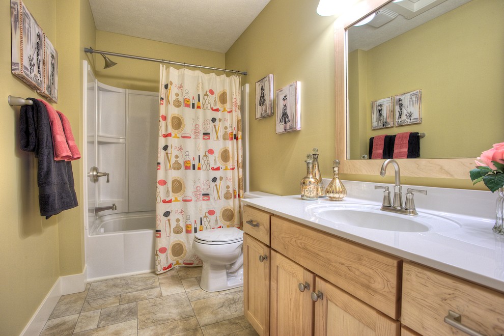 Foto på ett vintage badrum för barn, med ett integrerad handfat, släta luckor, skåp i ljust trä, marmorbänkskiva, en dusch/badkar-kombination, en toalettstol med separat cisternkåpa, beige väggar och linoleumgolv