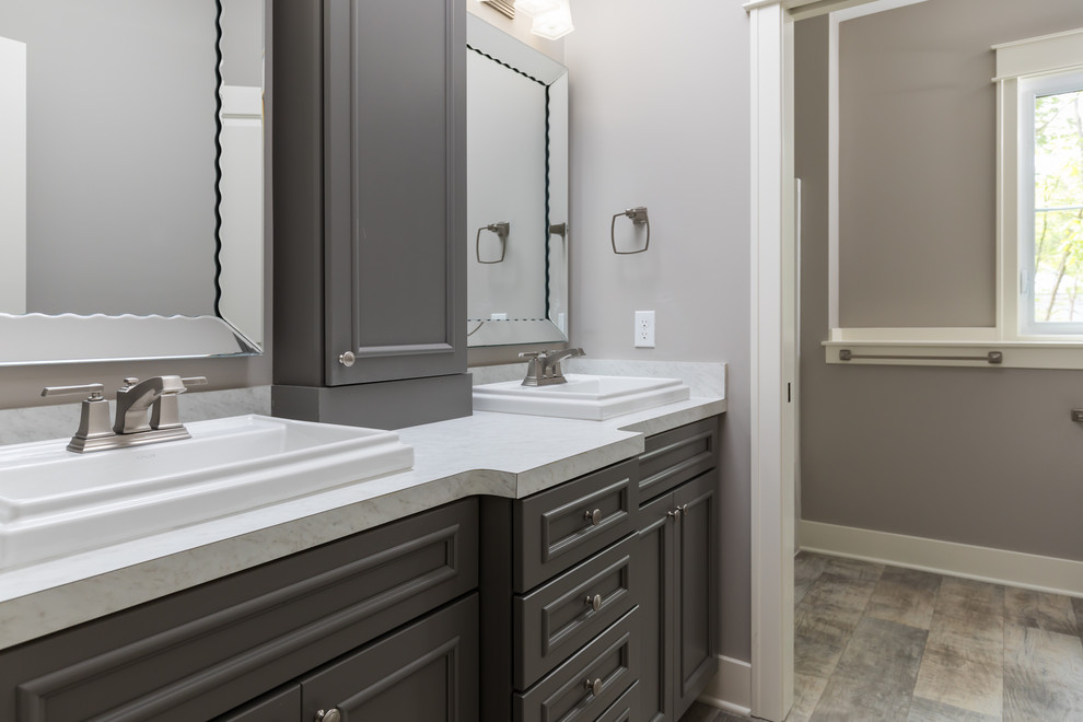 Photo of a large modern family bathroom in Grand Rapids with grey cabinets, a shower/bath combination, a one-piece toilet, grey walls, laminate floors, laminate worktops, beige floors and a shower curtain.