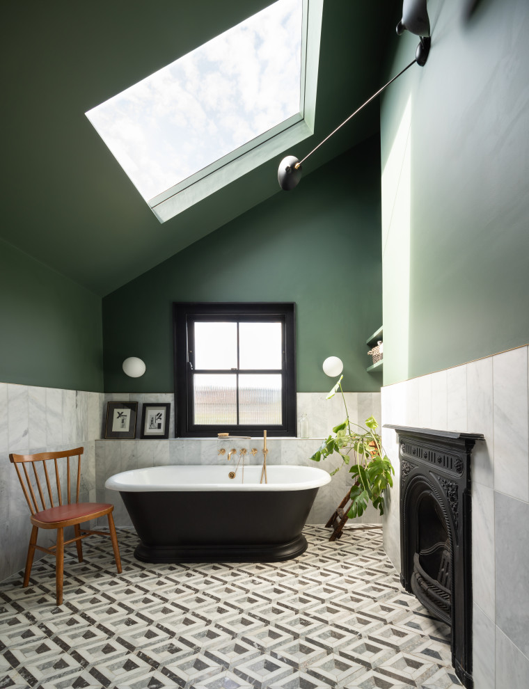 ロンドンにあるエクレクティックスタイルのおしゃれな浴室 (置き型浴槽、白いタイル、緑の壁、マルチカラーの床、三角天井) の写真