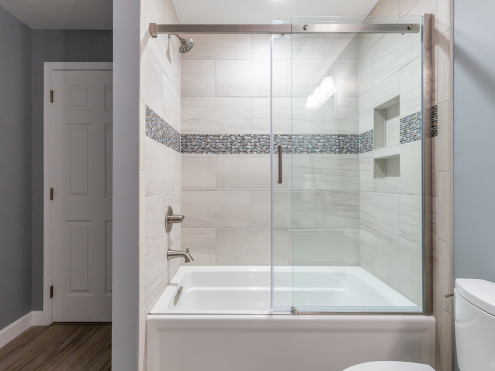 Photo of a medium sized contemporary family bathroom in DC Metro with shaker cabinets, white cabinets, an alcove bath, a shower/bath combination, a two-piece toilet, beige tiles, porcelain tiles, grey walls, porcelain flooring, a submerged sink, granite worktops, beige floors, a sliding door and grey worktops.