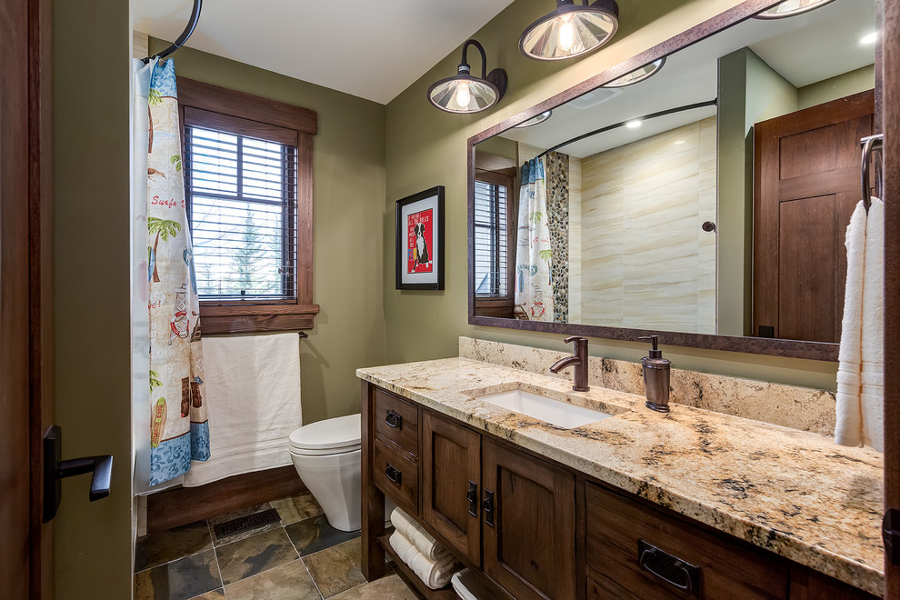Inspiration for a large traditional family bathroom in Calgary with a submerged sink, freestanding cabinets, dark wood cabinets, granite worktops, an alcove bath, a shower/bath combination, a one-piece toilet, beige tiles, porcelain tiles, slate flooring and green walls.