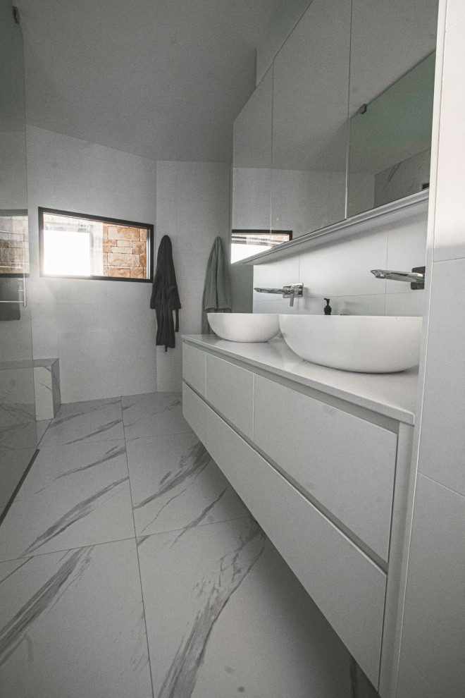 Esempio di un'ampia stanza da bagno minimalista con ante bianche, pavimento con piastrelle in ceramica, top in quarzo composito, top bianco, due lavabi e mobile bagno sospeso