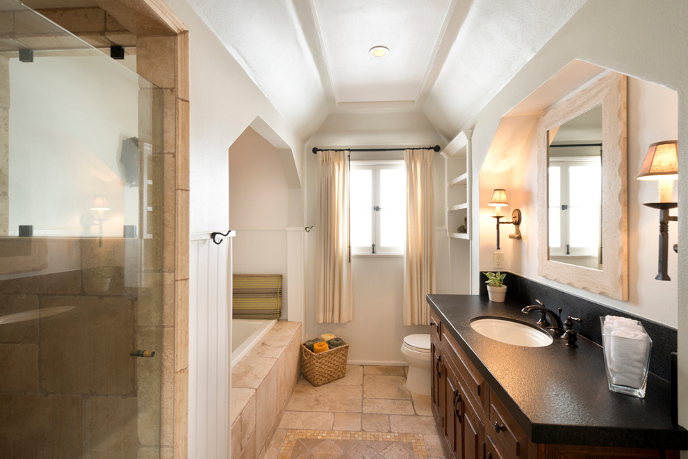 Diseño de cuarto de baño rectangular clásico renovado con lavabo bajoencimera, armarios con paneles con relieve, puertas de armario de madera en tonos medios, bañera empotrada y baldosas y/o azulejos beige