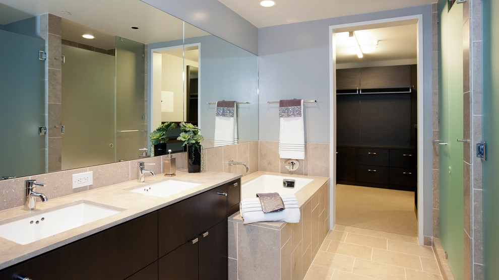 Cette image montre une grande salle de bain minimaliste en bois foncé avec un lavabo encastré, un placard à porte plane, un plan de toilette en carrelage, une baignoire encastrée, un carrelage beige, des carreaux de céramique, un mur bleu et un sol en carrelage de céramique.
