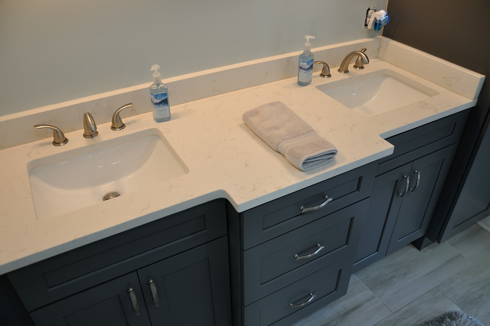 Cette photo montre une salle de bain tendance avec des portes de placard blanches, un lavabo encastré et un plan de toilette en quartz modifié.