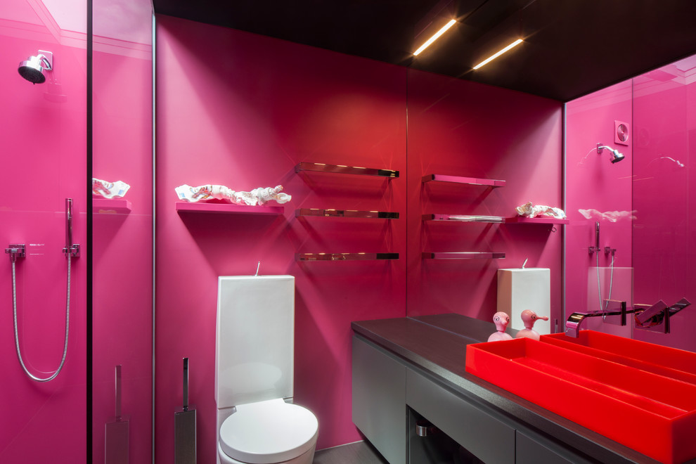 Réalisation d'une petite salle de bain design avec une douche d'angle, WC à poser, un mur rose et une grande vasque.