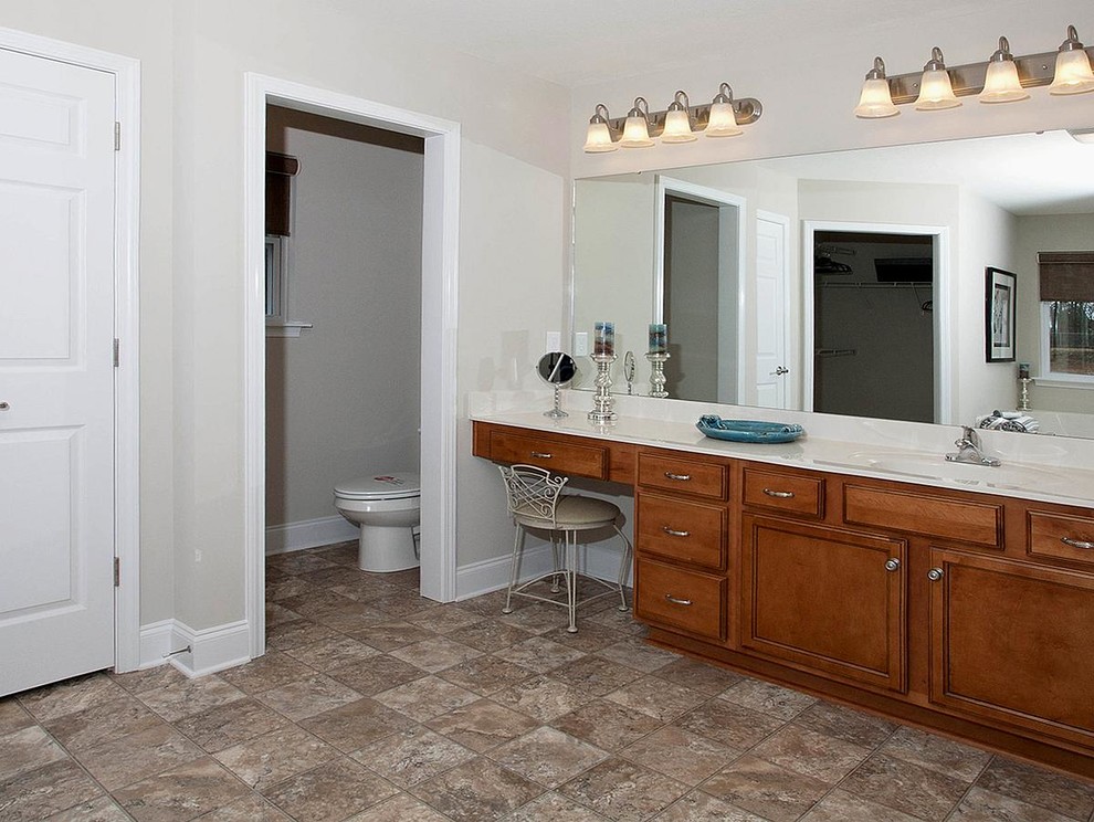 Bathroom - large traditional master vinyl floor bathroom idea in Raleigh with recessed-panel cabinets, medium tone wood cabinets, a two-piece toilet, white walls, an integrated sink and quartz countertops