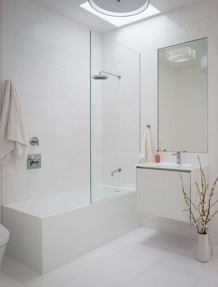 Idées déco pour une salle de bain moderne avec un placard à porte plane, des portes de placard blanches, un combiné douche/baignoire et un carrelage blanc.