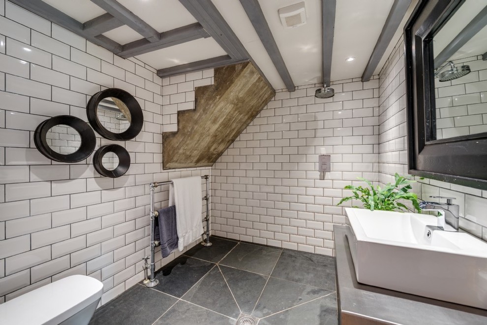 Bild på ett stort rustikt badrum med dusch, med möbel-liknande, våtrum, en vägghängd toalettstol, vit kakel, keramikplattor, vita väggar, skiffergolv, ett avlångt handfat, bänkskiva i rostfritt stål och grått golv