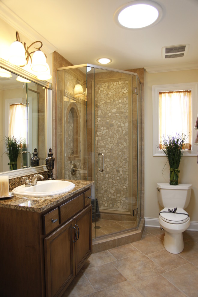 Inspiration för mellanstora klassiska badrum med dusch, med luckor med upphöjd panel, skåp i mellenmörkt trä, en hörndusch, en toalettstol med separat cisternkåpa, brun kakel, kakel i småsten, gula väggar, klinkergolv i keramik, ett nedsänkt handfat och granitbänkskiva