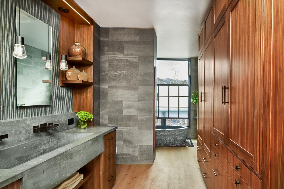 Aménagement d'une salle de bain principale contemporaine en bois brun avec un placard à porte shaker, une baignoire indépendante, un carrelage gris, parquet clair, un lavabo intégré, un sol beige et un plan de toilette gris.