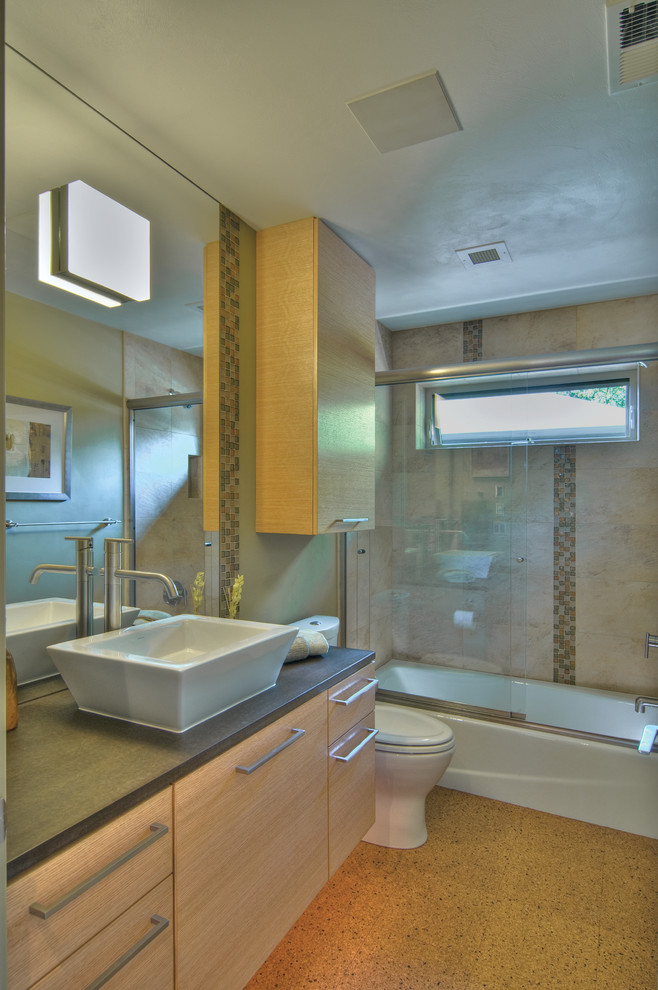 На фото: маленькая ванная комната в стиле неоклассика (современная классика) с настольной раковиной, плоскими фасадами, светлыми деревянными фасадами, ванной в нише, душем над ванной, раздельным унитазом, разноцветной плиткой, стеклянной плиткой, серыми стенами и пробковым полом для на участке и в саду с