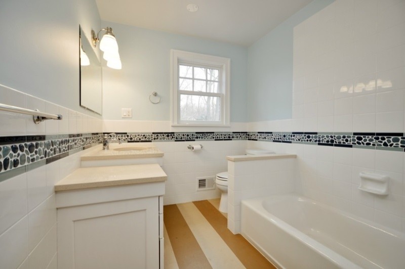 Bathroom - mid-sized coastal kids' beige tile and pebble tile cork floor and multicolored floor bathroom idea in New York with recessed-panel cabinets, white cabinets, a two-piece toilet, blue walls, an undermount sink, quartz countertops and beige countertops