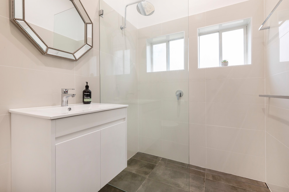 Diseño de cuarto de baño moderno pequeño con armarios tipo mueble, puertas de armario blancas, ducha abierta, sanitario de dos piezas, paredes blancas, aseo y ducha, lavabo integrado y suelo negro