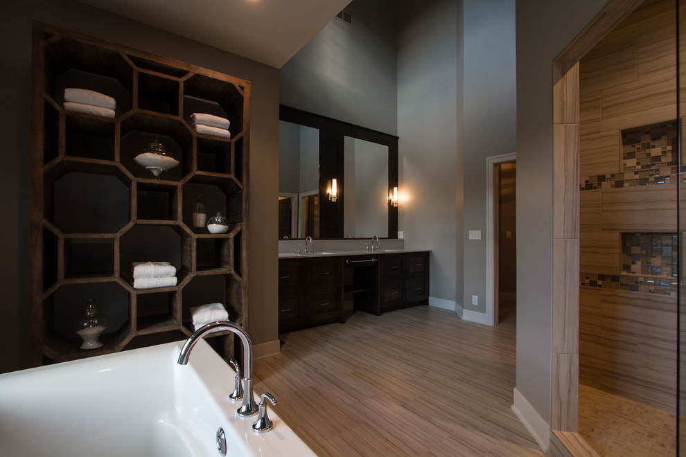 This is an example of a large traditional ensuite bathroom in Omaha with shaker cabinets, dark wood cabinets, a freestanding bath, an alcove shower, a two-piece toilet, brown walls, a submerged sink and solid surface worktops.