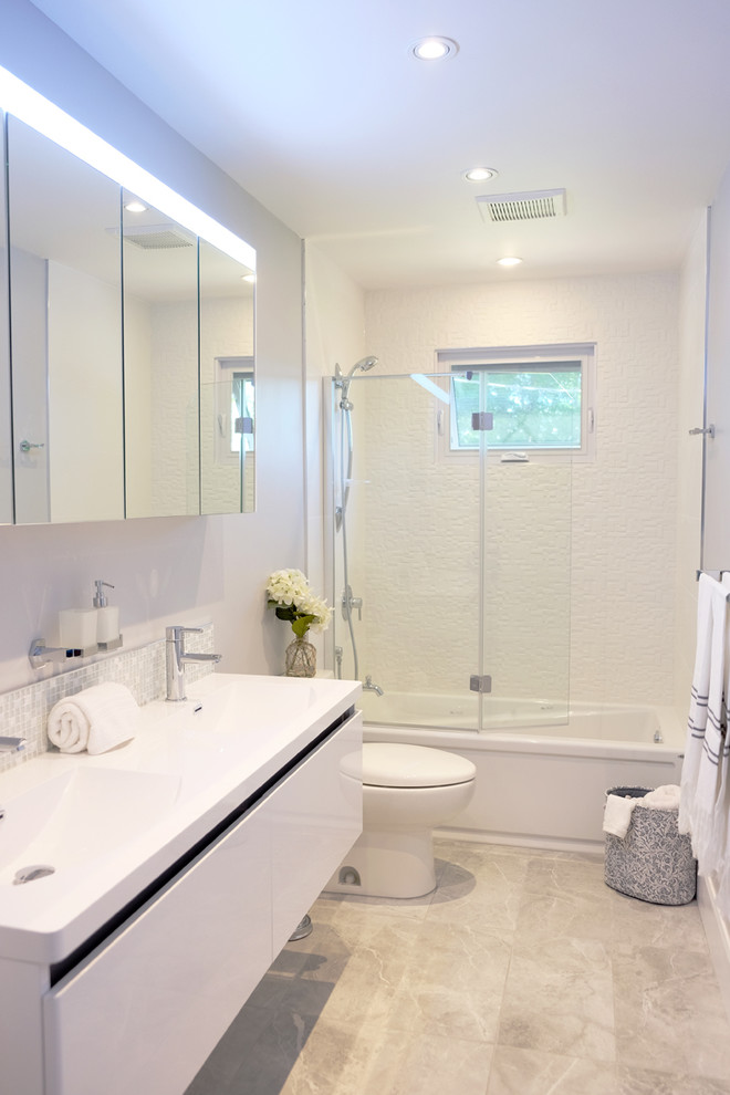 Idéer för att renovera ett litet funkis en-suite badrum, med släta luckor, vita skåp, ett badkar i en alkov, en dusch/badkar-kombination, en toalettstol med hel cisternkåpa, vit kakel, porslinskakel, grå väggar, klinkergolv i porslin, ett undermonterad handfat och bänkskiva i akrylsten