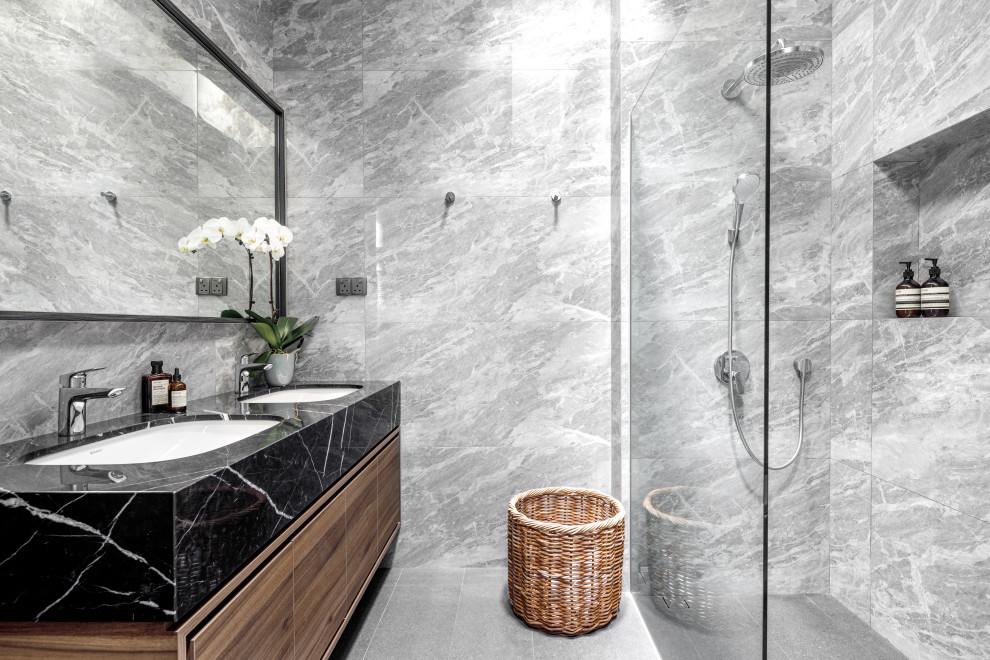 Immagine di una stanza da bagno design di medie dimensioni con ante lisce, ante in legno scuro, piastrelle grigie, lavabo sottopiano, pavimento grigio e top nero