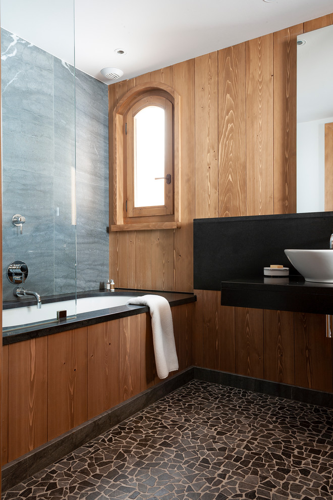 Ejemplo de cuarto de baño principal escandinavo de tamaño medio con bañera encastrada, ducha a ras de suelo, suelo de baldosas tipo guijarro, encimera de ónix y encimeras negras