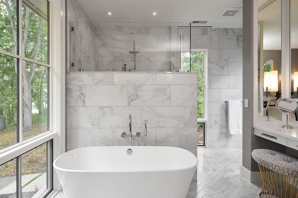 Cette photo montre une salle de bain chic avec des portes de placard blanches, une baignoire indépendante, une douche d'angle, un mur gris, un sol gris, une cabine de douche à porte battante et un plan de toilette blanc.