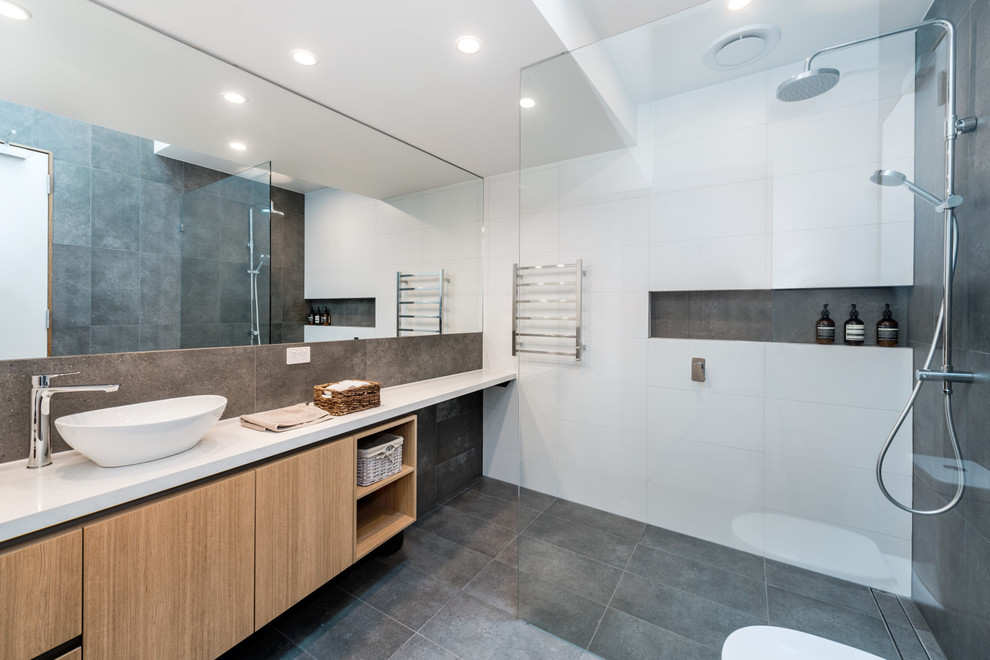 Пример оригинального дизайна: ванная комната среднего размера в современном стиле с коричневыми фасадами, душевой комнатой, раздельным унитазом, белой плиткой, керамической плиткой, серыми стенами, полом из цементной плитки, душевой кабиной, столешницей из гранита, серым полом, открытым душем и белой столешницей