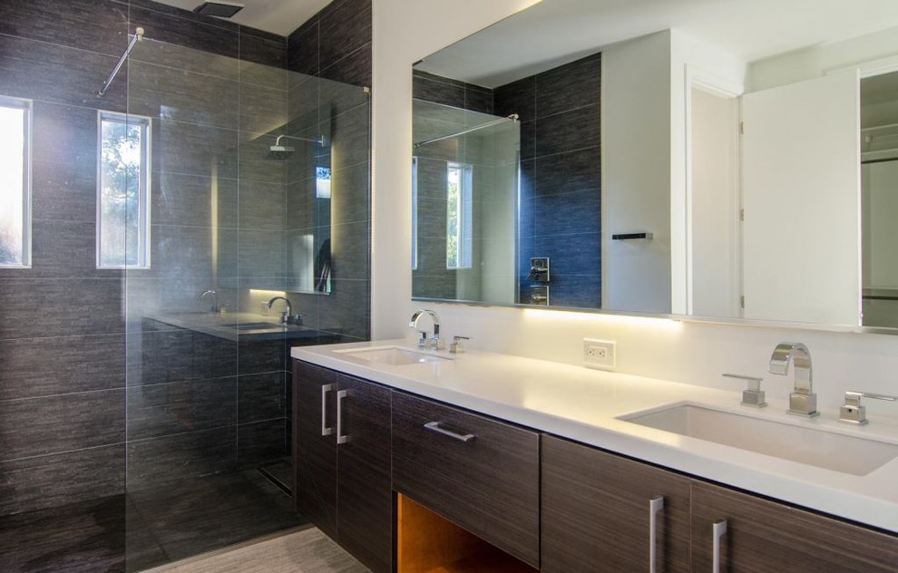 Geräumiges Modernes Badezimmer En Suite mit braunen Schränken, Eckdusche, schwarzen Fliesen, weißer Wandfarbe, braunem Holzboden, Einbauwaschbecken, braunem Boden, Falttür-Duschabtrennung und weißer Waschtischplatte in Tampa