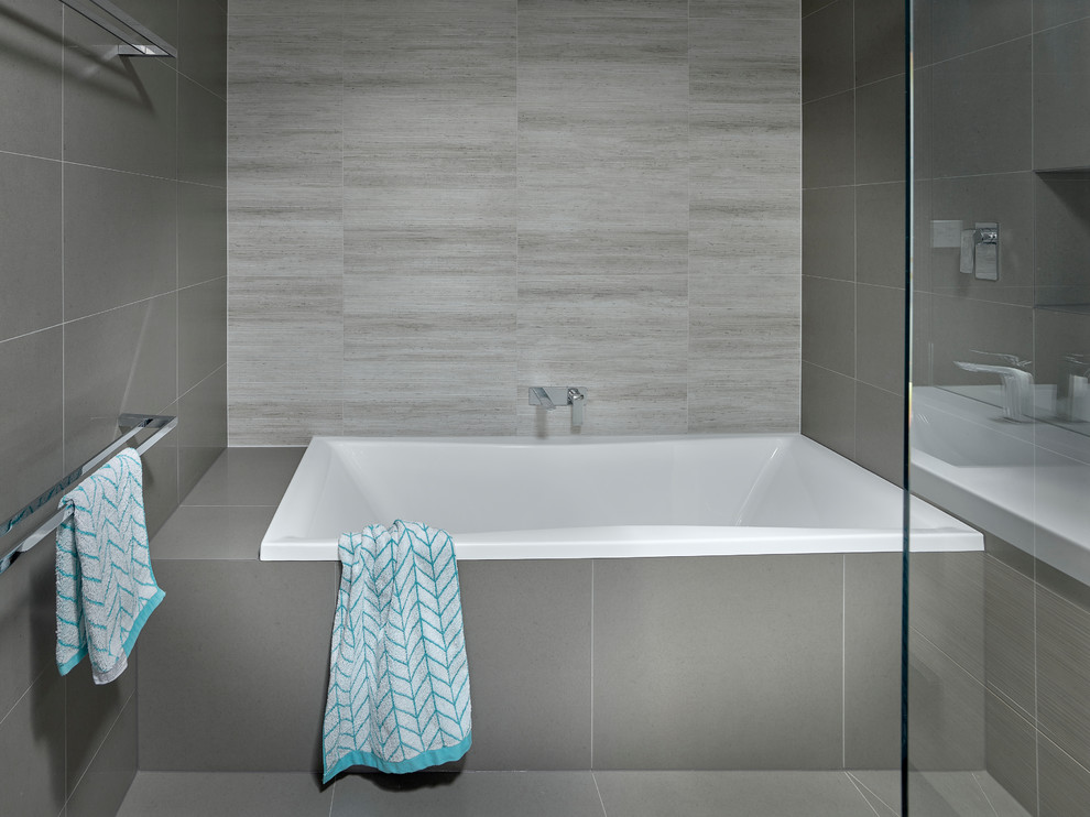 Esempio di una piccola stanza da bagno padronale design con lavabo integrato, ante in legno chiaro, vasca da incasso, doccia aperta, piastrelle grigie e pareti grigie