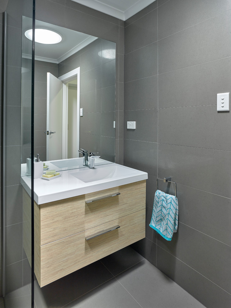 Foto di una piccola stanza da bagno padronale minimal con lavabo integrato, ante in legno chiaro, vasca da incasso, doccia aperta, piastrelle grigie e pareti grigie