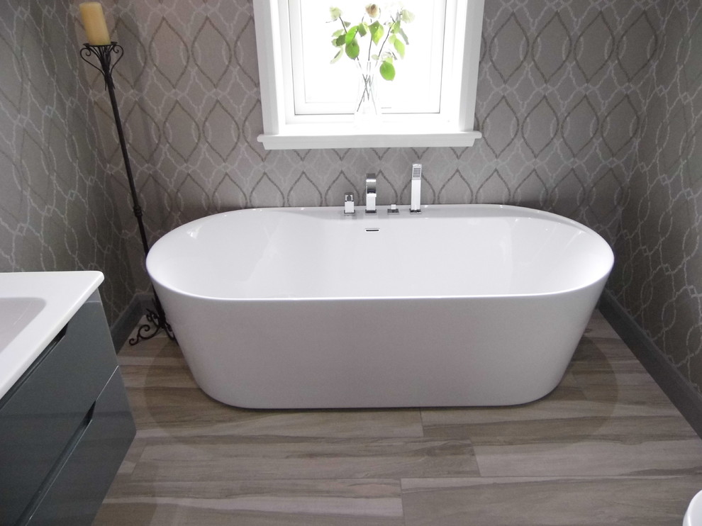 Foto di una stanza da bagno design di medie dimensioni con vasca freestanding, piastrelle effetto legno e pareti grigie