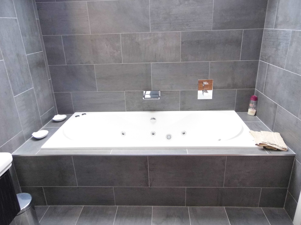 Ispirazione per una stanza da bagno padronale design di medie dimensioni con vasca idromassaggio, piastrelle grigie, piastrelle in gres porcellanato, pareti grigie e pavimento in gres porcellanato