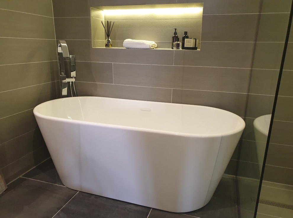 Inspiration for a large modern ensuite bathroom in Other with flat-panel cabinets, brown cabinets, a freestanding bath, a built-in shower, a wall mounted toilet, grey tiles, ceramic tiles, grey walls, ceramic flooring, a console sink, wooden worktops, grey floors, an open shower and brown worktops.
