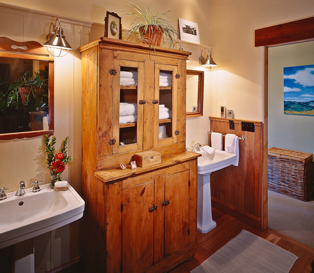 Foto de cuarto de baño principal rural grande con lavabo tipo consola, puertas de armario de madera oscura, paredes beige y suelo de madera en tonos medios