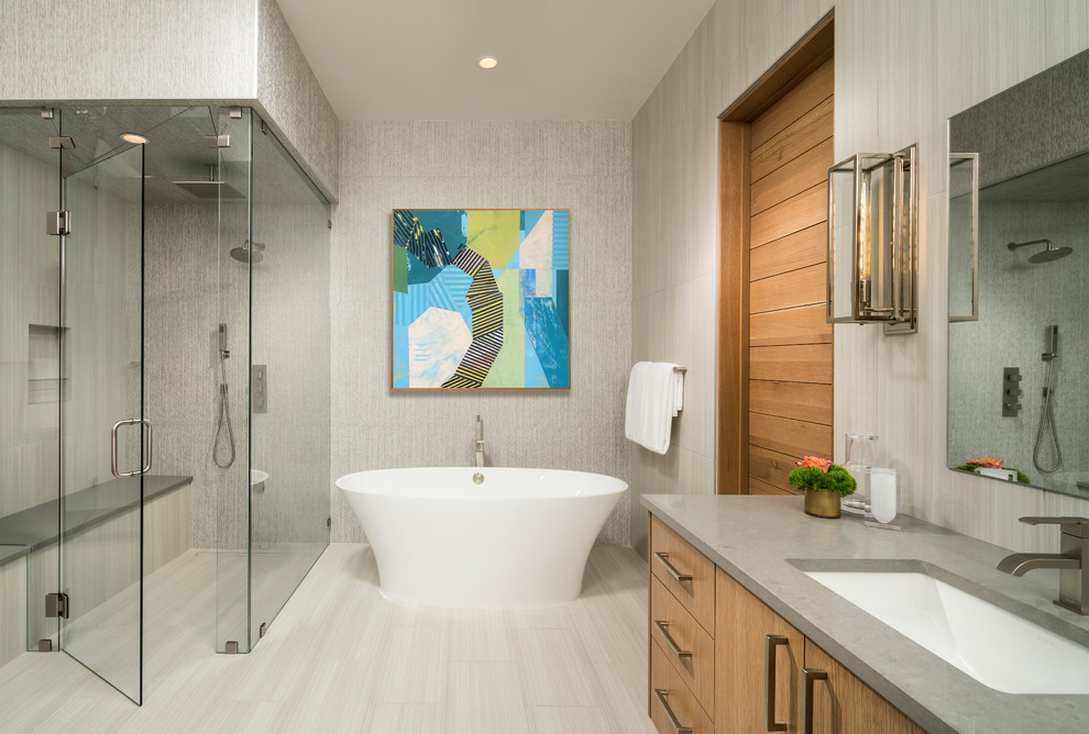 Aménagement d'une salle de bain contemporaine en bois brun avec un placard à porte plane, une baignoire indépendante, une douche à l'italienne, un mur beige, un lavabo encastré, un sol beige, une cabine de douche à porte battante et un plan de toilette gris.