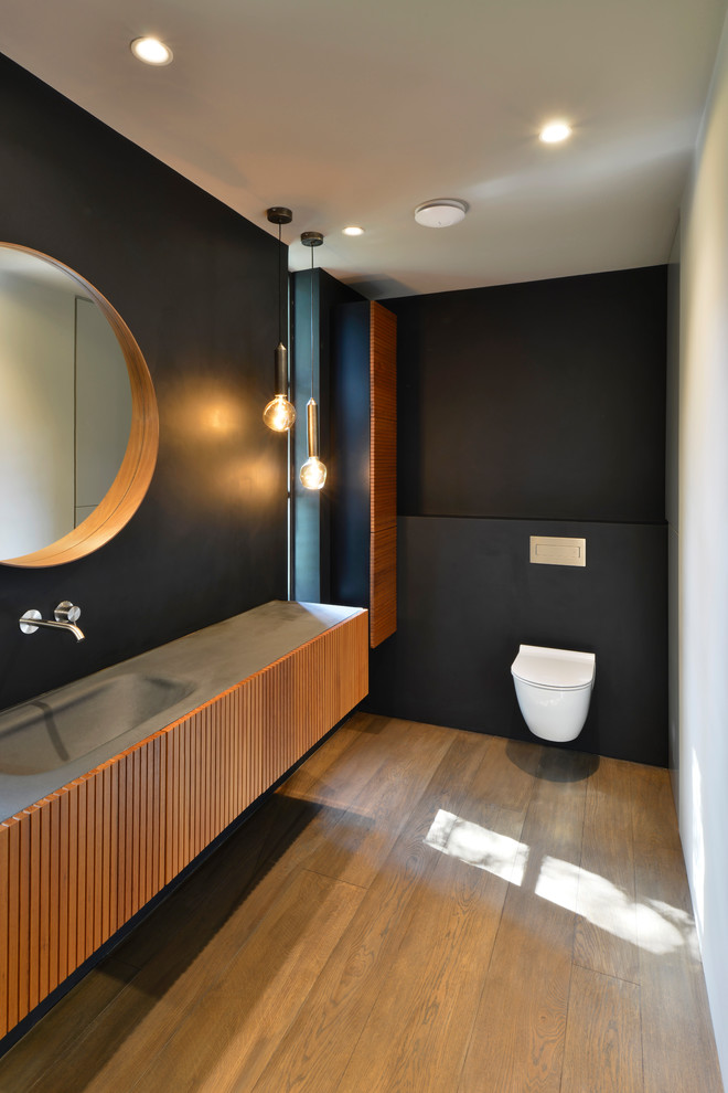 Inredning av ett modernt grå grått badrum, med luckor med lamellpanel, skåp i mellenmörkt trä, en öppen dusch, en vägghängd toalettstol, blå väggar, mellanmörkt trägolv, ett nedsänkt handfat, bänkskiva i betong, brunt golv och med dusch som är öppen