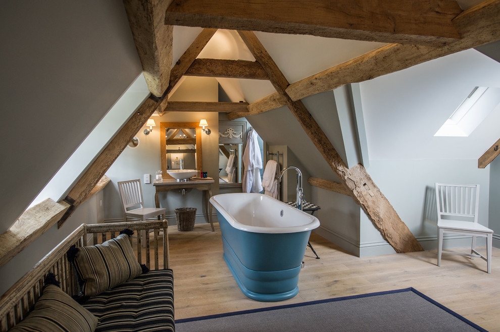 Пример оригинального дизайна: ванная комната среднего размера в стиле кантри с отдельно стоящей ванной, серыми стенами, светлым паркетным полом, настольной раковиной, бежевым полом и столешницей из дерева