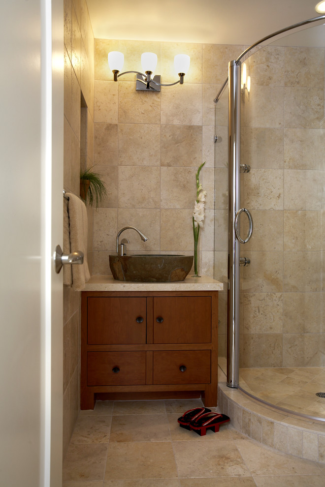 Cette image montre une salle d'eau asiatique en bois brun de taille moyenne avec une vasque, un placard à porte plane, un plan de toilette en granite, une douche d'angle, un sol en travertin, un mur beige et du carrelage en travertin.