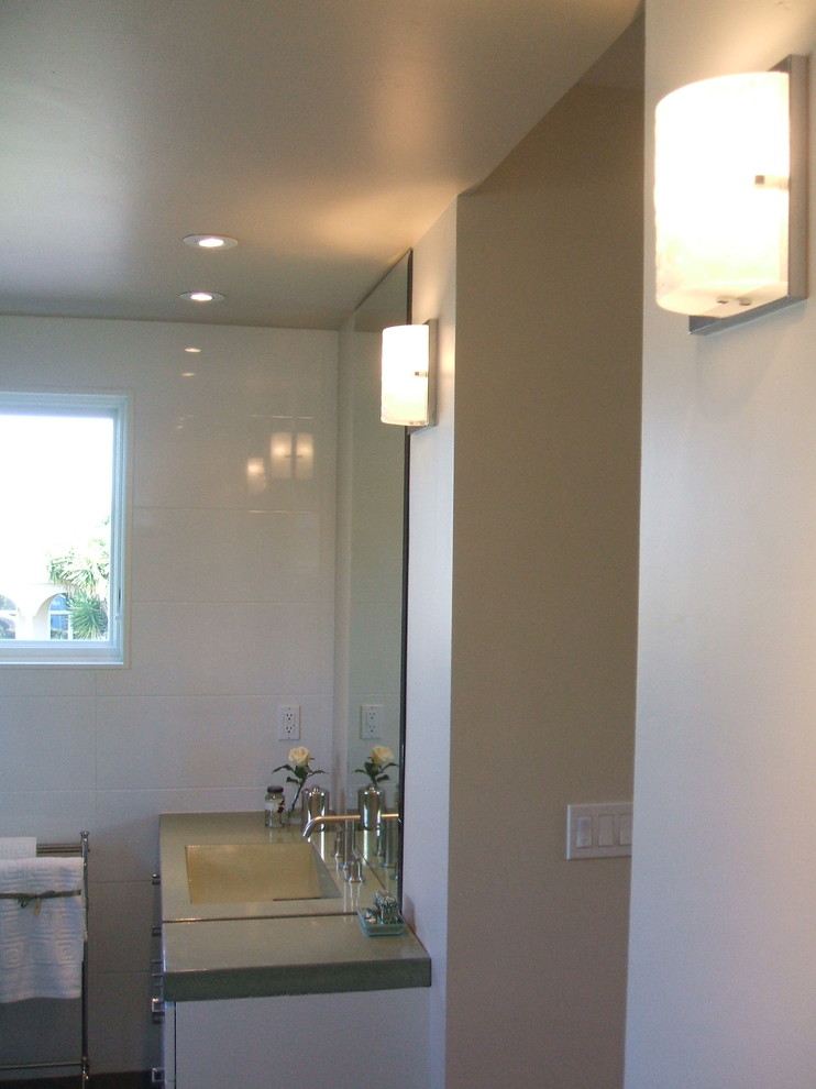 Immagine di una piccola stanza da bagno con doccia minimalista con lavabo integrato, ante lisce, ante bianche, piastrelle bianche, piastrelle in gres porcellanato e pareti bianche
