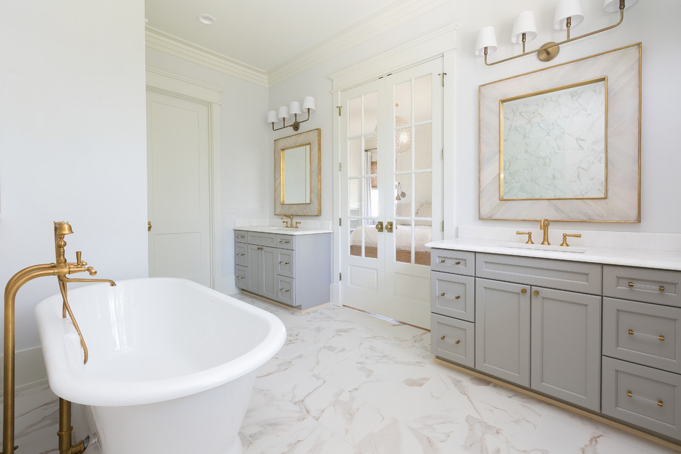Cette photo montre une grande salle de bain principale nature avec des portes de placard grises, une baignoire indépendante, une douche ouverte, aucune cabine, un placard avec porte à panneau encastré, un carrelage gris, un carrelage blanc, du carrelage en marbre, un mur blanc, un sol en marbre, un lavabo encastré, un plan de toilette en marbre, un sol blanc et un plan de toilette blanc.