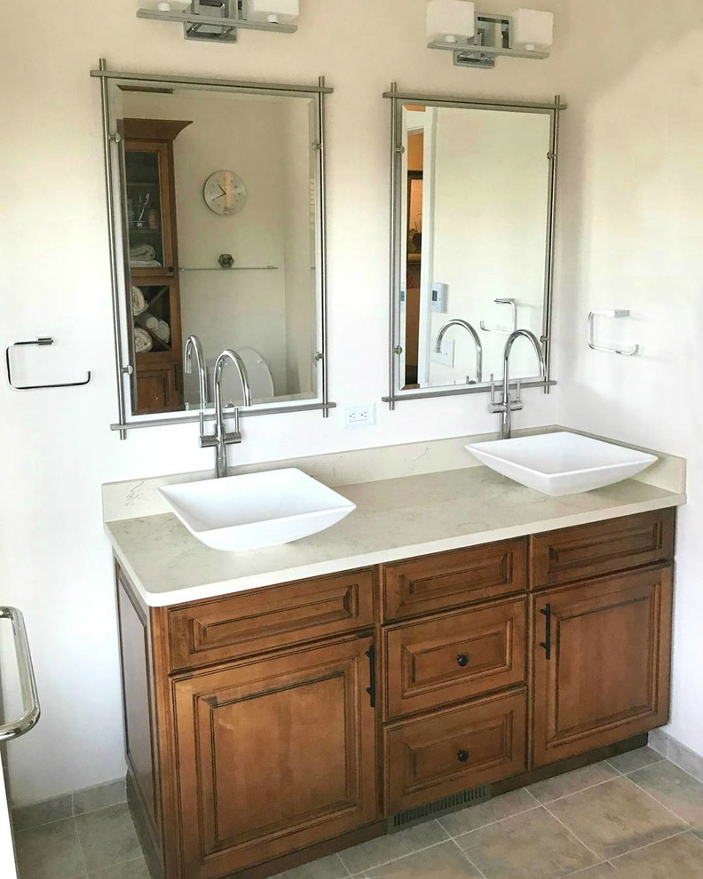 This is an example of a medium sized classic ensuite bathroom in Seattle with raised-panel cabinets, medium wood cabinets, a freestanding bath, a corner shower, a two-piece toilet, beige tiles, marble tiles, beige walls, porcelain flooring, a vessel sink, engineered stone worktops, brown floors and a hinged door.