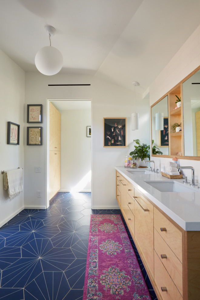 Cette image montre une salle de bain principale vintage en bois clair avec un placard à porte plane, une baignoire indépendante, une douche ouverte, un carrelage bleu, des carreaux de porcelaine, un mur blanc, un sol en carrelage de porcelaine, un lavabo encastré, un plan de toilette en quartz modifié, un sol bleu, aucune cabine et un plan de toilette blanc.